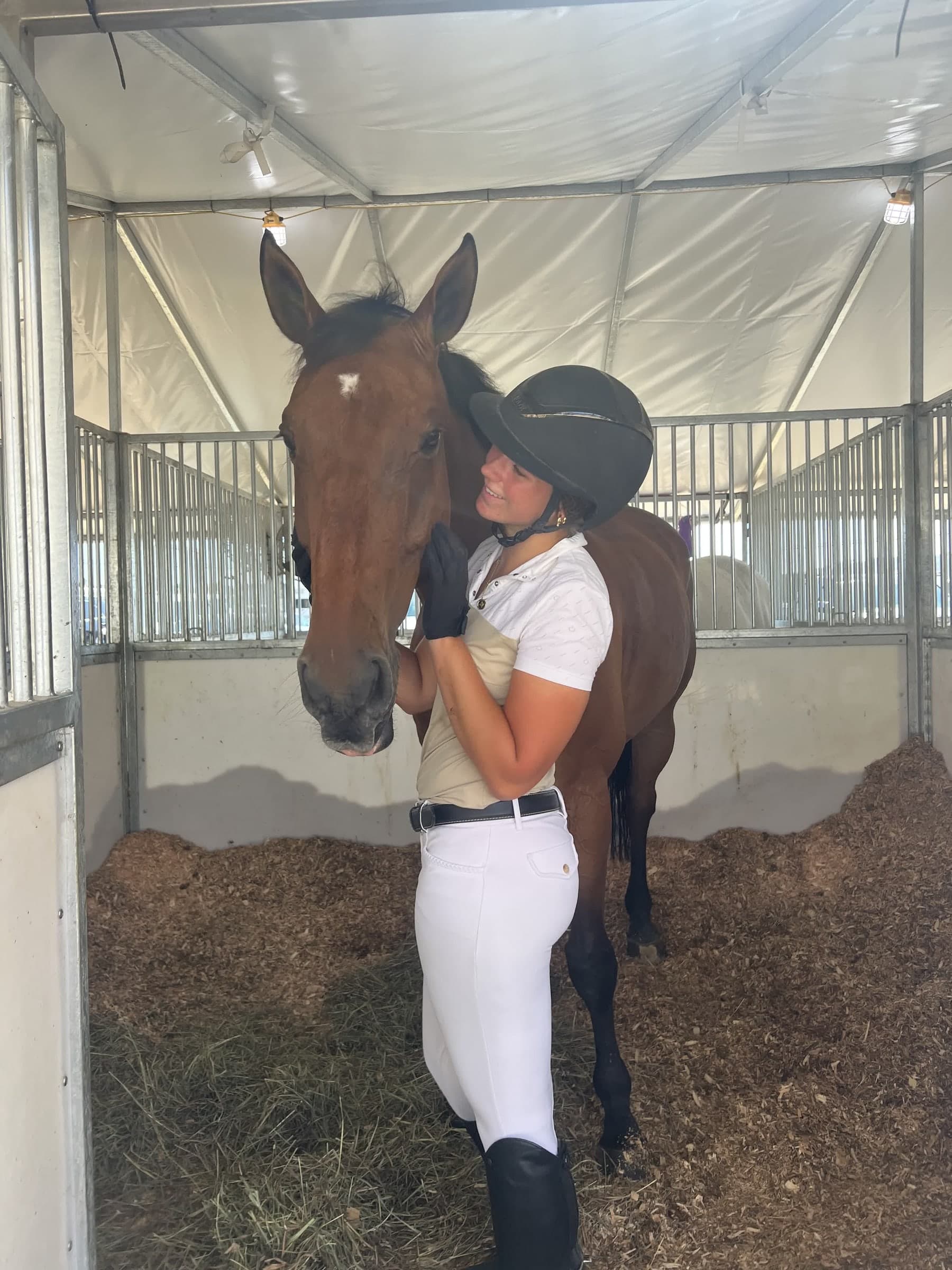 A rider sharing a quiet moment with a horse in its stall