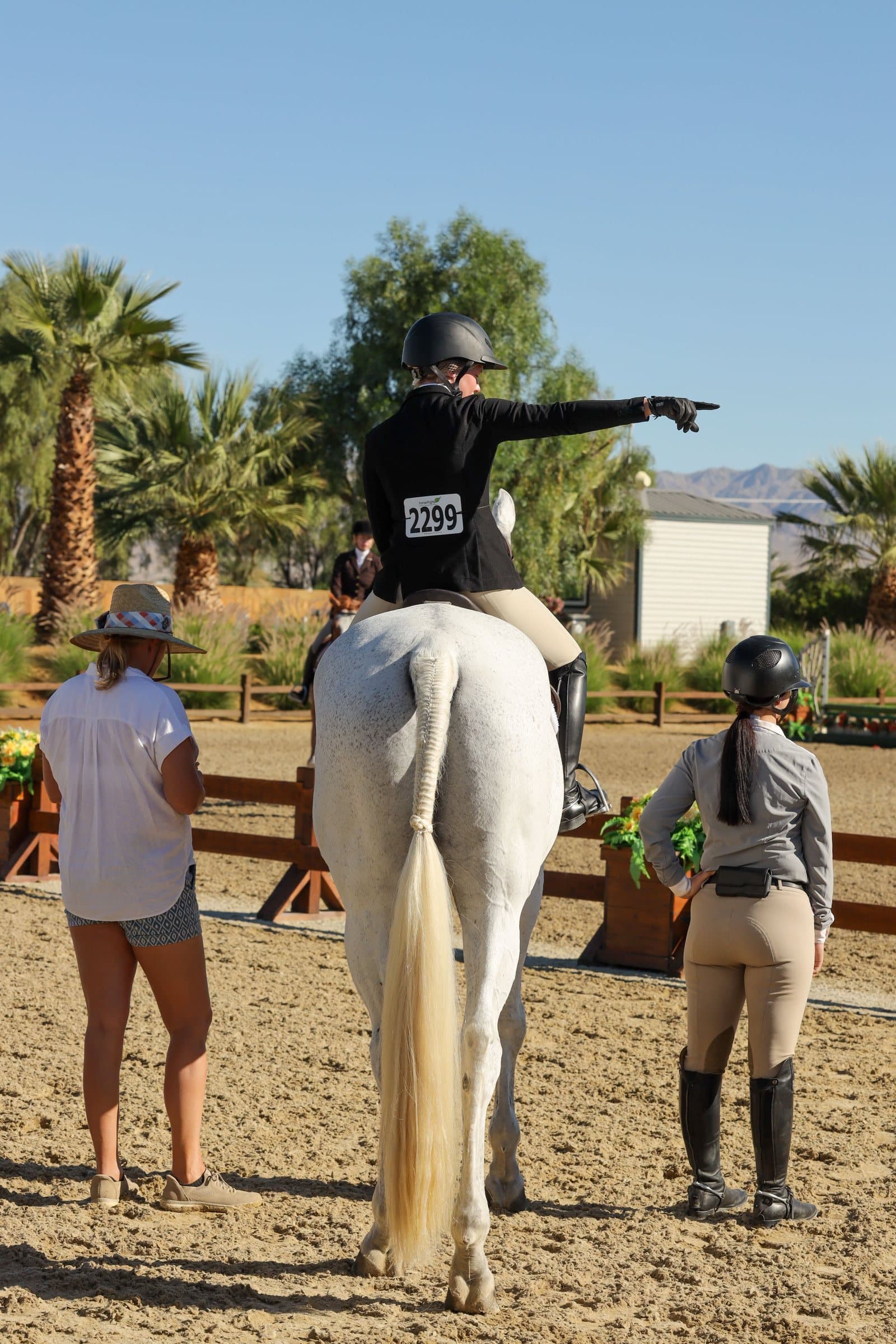 A rider on a grey horse talking through the plan with two people on the ground