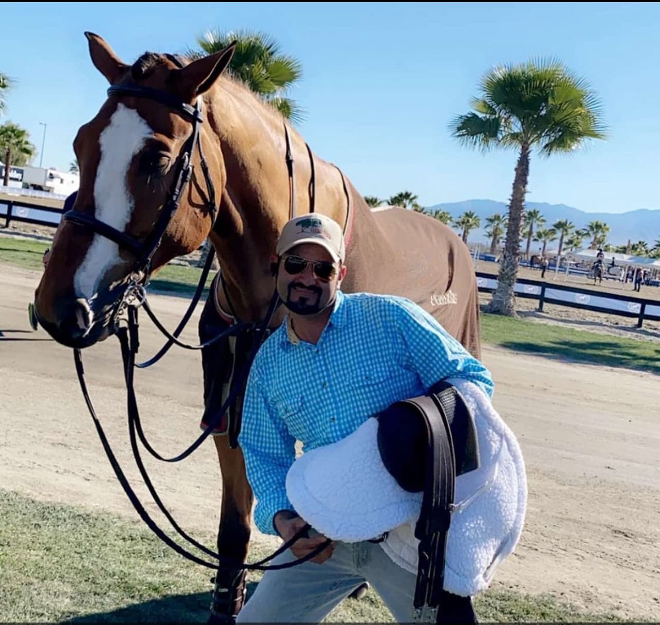 A groom standing beside a chestnut horse with its tack