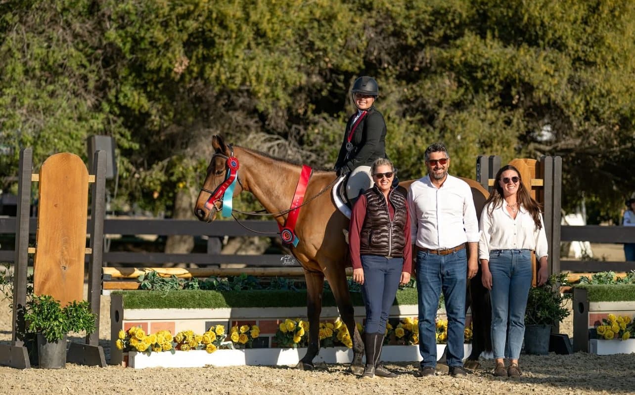 Riders and supporters gathered around a horse at a horse show